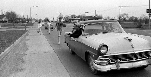 Bill Bishop leans out of Mike Friese's 56 Ford to protect dribbling students