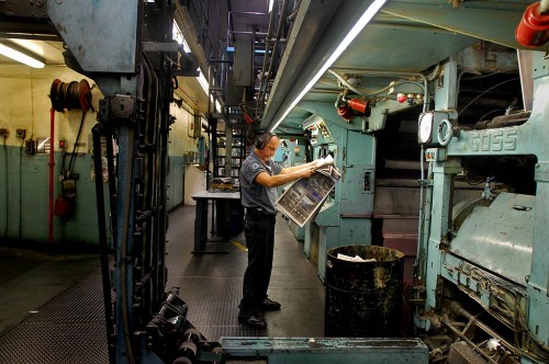 Press operator checks paper fresh off the press