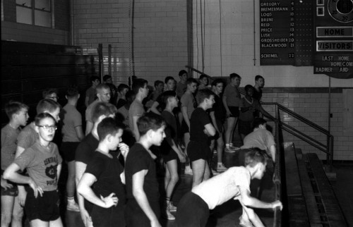 Central High School boys, wearing reversible gym suits, wait in bleachers
